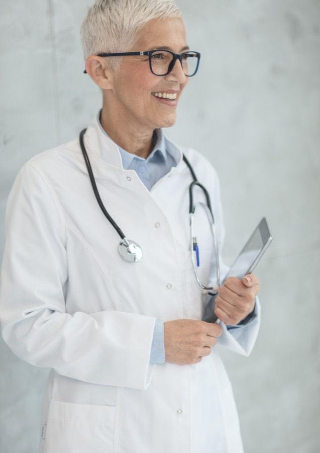 A consultant in a white coat holding a tablet